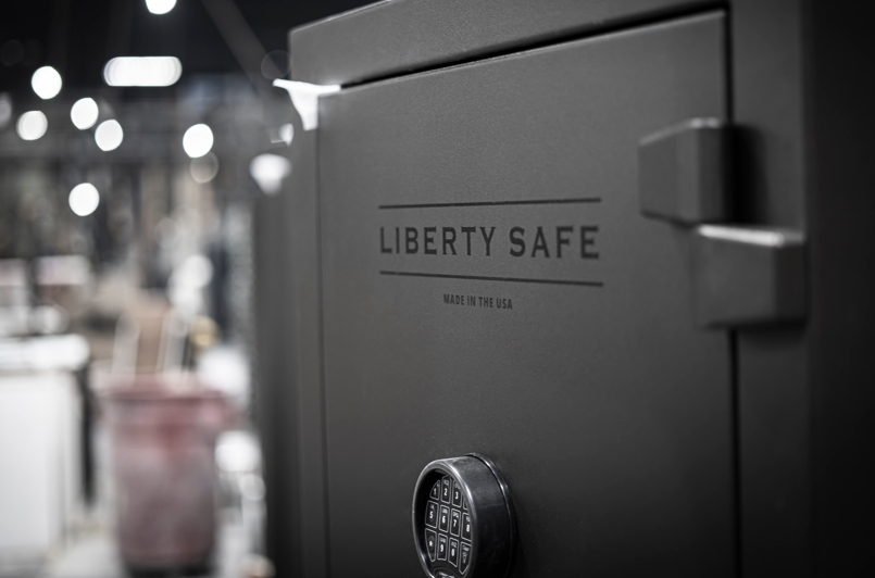 Close-up of a dark gray Liberty Safe with the brand name embossed on the door and a combination dial lock.
